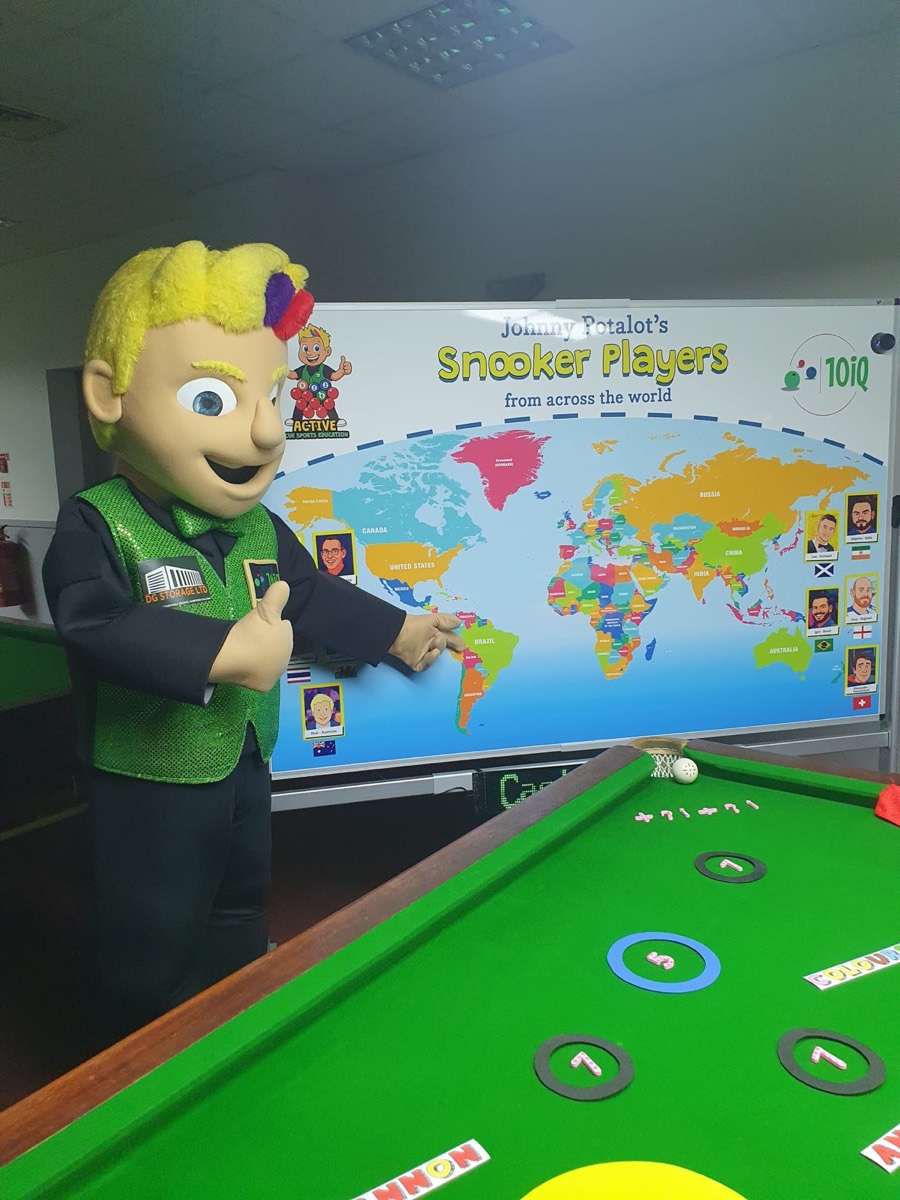 Johnny Potalot pointing out a country on the world map beside the table