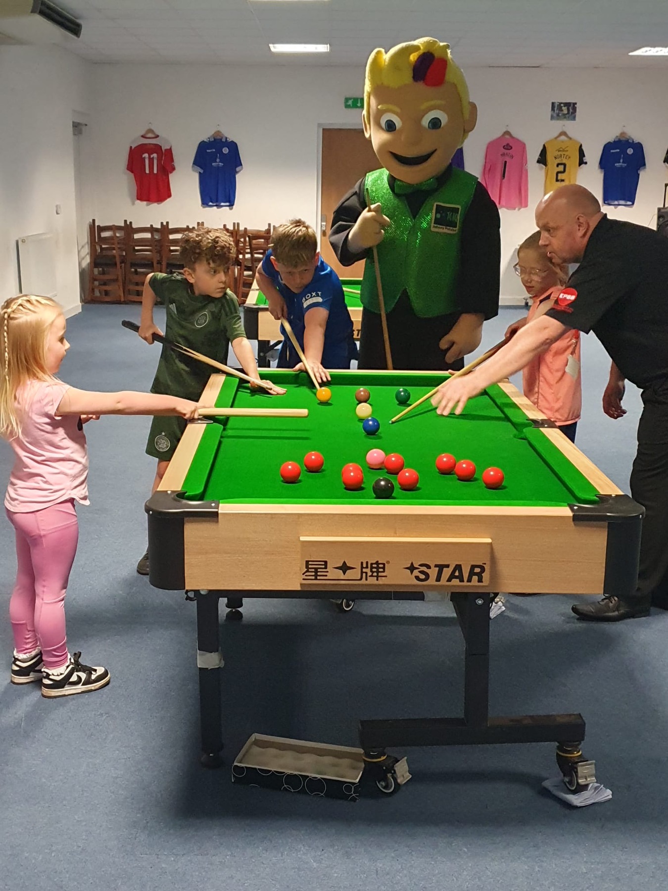 Pupils lining up shots at a portable snooker table